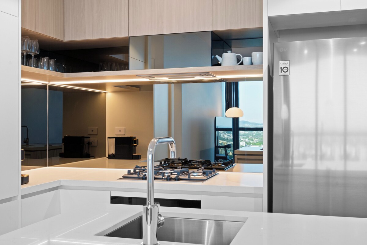 A modern kitchen with a stainless steel sink, wooden cabinets, and a view through the window.