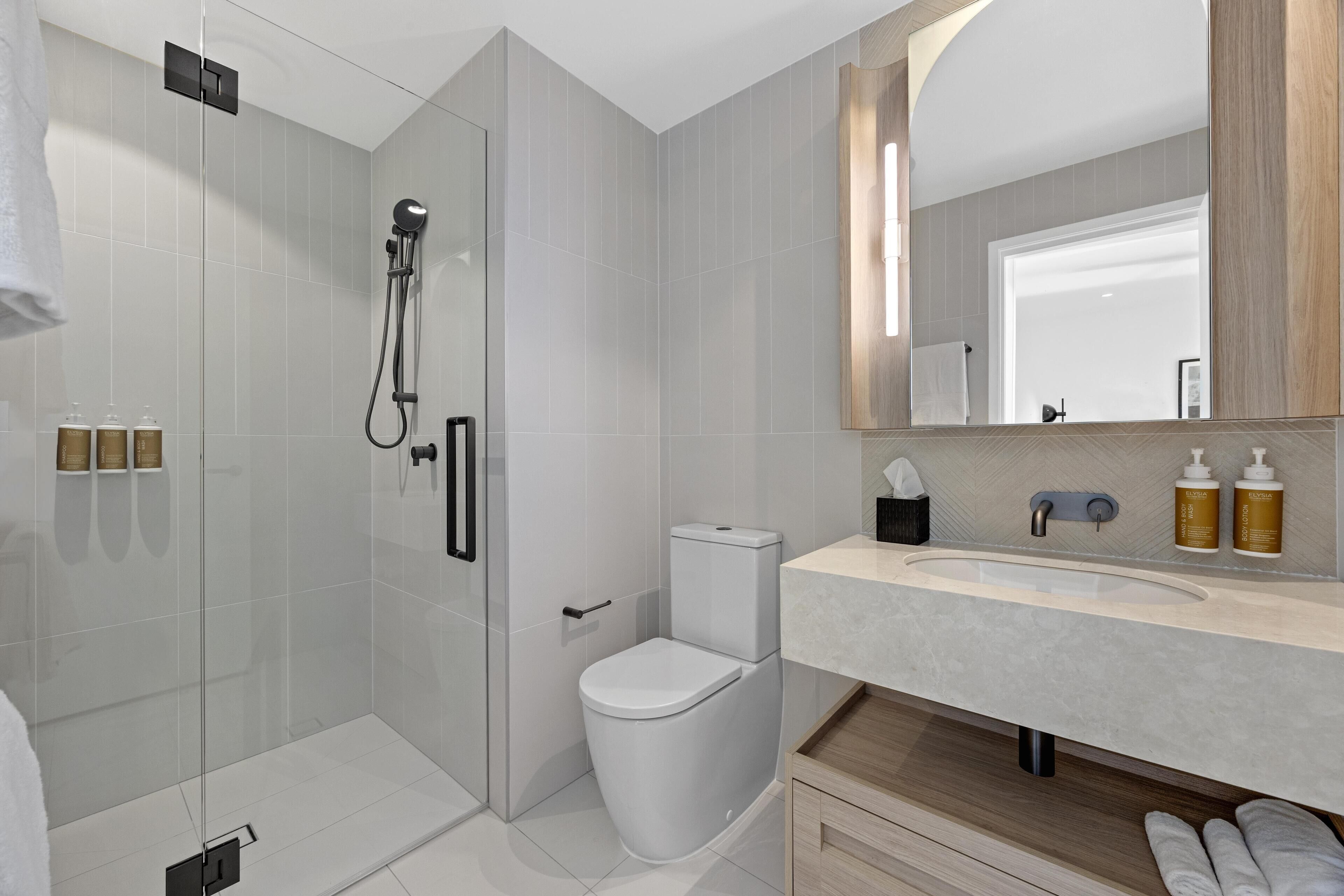 A modern bathroom with a glass-enclosed shower, a toilet, and a vanity with a sink.