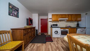 A compact kitchen with wooden cabinets, a washing machine, and a microwave. - Large, fully-equipped 8-pers apt (Allos)
