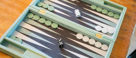 Primer plano de un tablero de backgammon con piezas y dados sobre una superficie de madera.