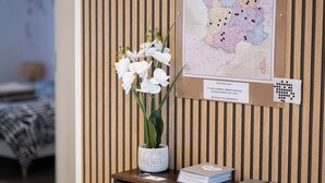 Un mur recouvert de panneaux de bois, orné d’une carte et surmonté d’un petit bureau agrémenté d’un vase contenant des orchidées blanches.