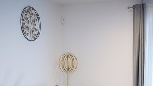 Un salon moderne avec un canapé gris, une petite table d’appoint, un lampadaire et un élément décoratif mural.