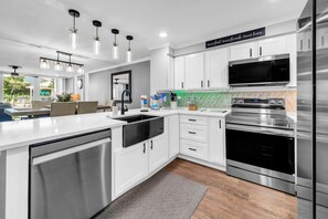 A modern kitchen with white cabinetry, stainless steel appliances, and pendant lighting.