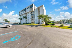 A modern building with multiple balconies, a parking lot, and a clear blue sky. - Dolphin Point 106C - Harbor Views & Boat Slip (Destin)