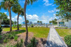 A pathway leading to a pool area with palm trees and a clear sky. - Dolphin Point 106C - Harbor Views & Boat Slip (Destin)