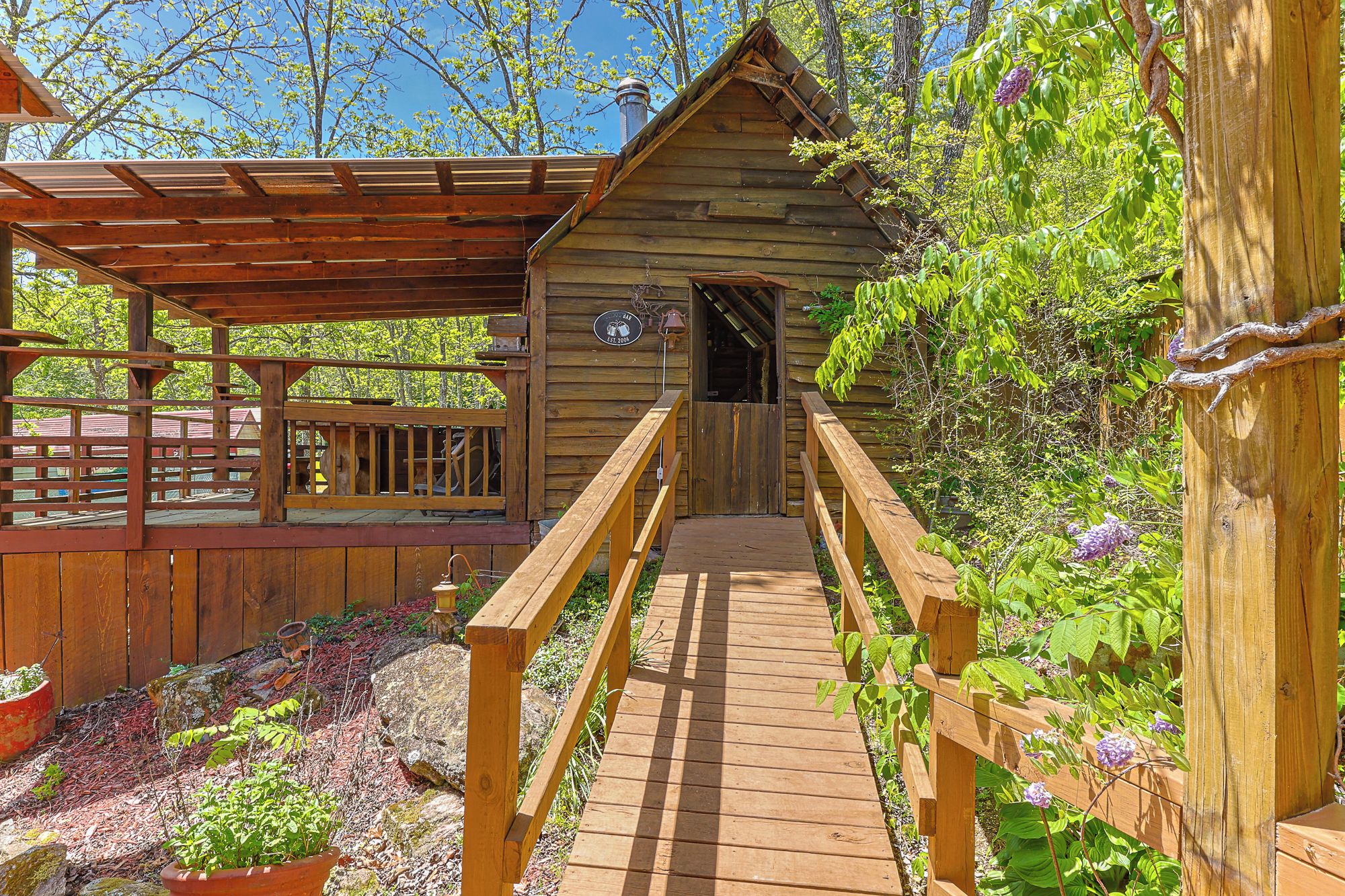 Eine Holzhütte mit überdachter Veranda und einer Holzbrücke, die dorthin führt.