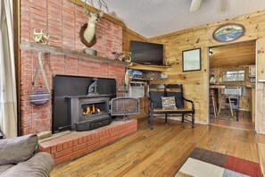 Una sala de estar acogedora con chimenea de ladrillo, un televisor montado en la pared y piso de madera.