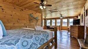 A wooden cabin interior with a bed, a television, and a ceiling fan. - NEW LISTING !!!  RUSTIC MEADOW AT LADYBUG LAKE (Morganton)