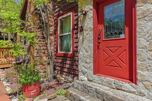 A stone building with a red door and a window, surrounded by greenery. - NEW LISTING !!! RUSTIC MEADOW AT LADYBUG LAKE (Morganton)