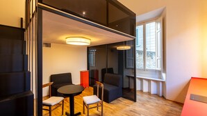A modern room with a round table, two chairs, a sofa, and a window with a view.