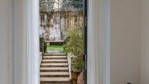 A view through a doorway to a set of stone steps leading to a garden area with a fence and greenery.