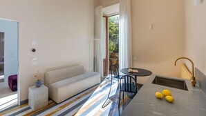 Ein modernes Wohnzimmer mit einer Couch, einem Esstisch und einer Küchenzeile mit Spüle und Zitronen.