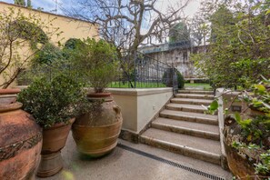 A stone staircase leading up to a balcony with potted plants and a metal railing. - Made by a Young Local Designer (Firenze)