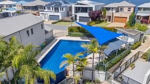 Zona residencial con piscina rodeada de palmeras y casas modernas.