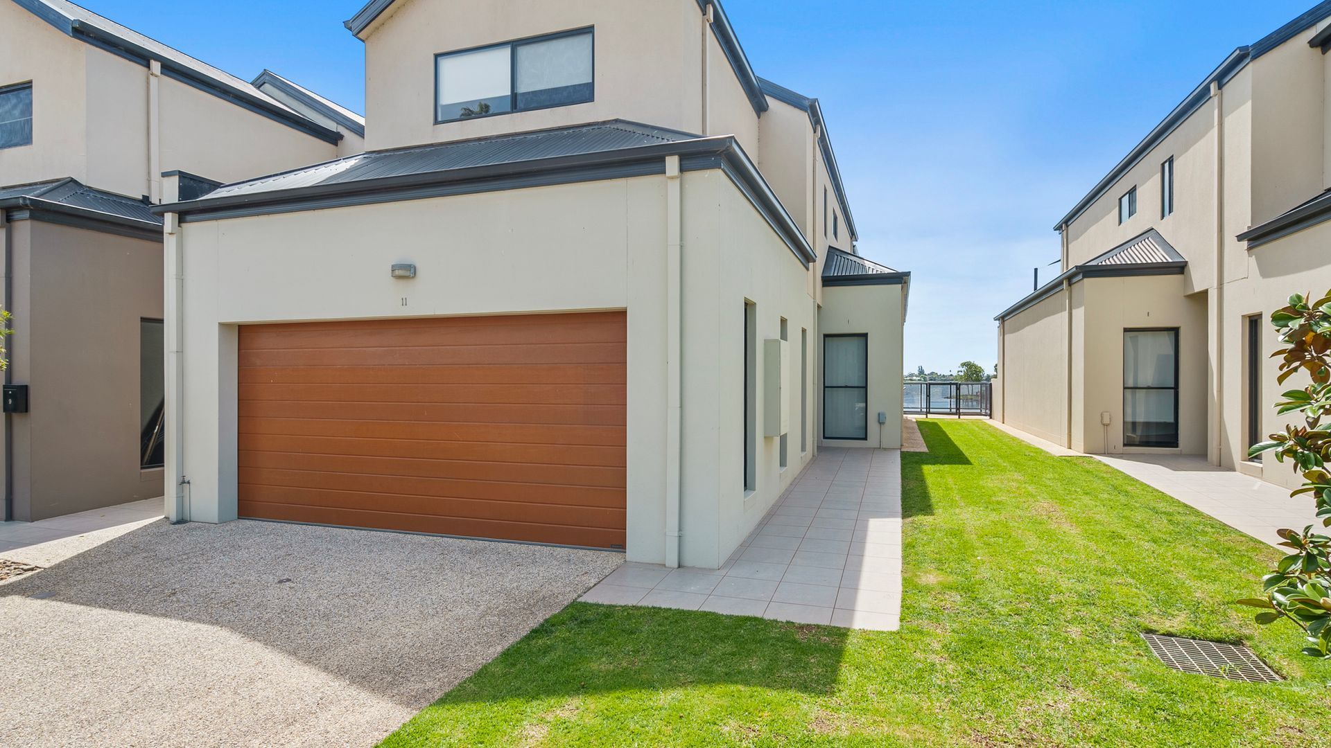 A modern residential building with a garage, a well-maintained lawn, and a clear sky.