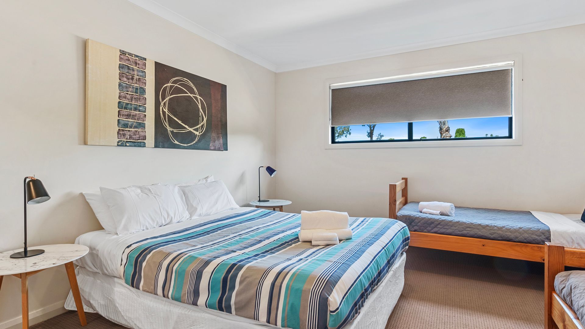 A bedroom with a large bed, a smaller bed, a desk, a chair, and a window with a view.