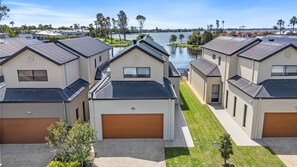 Un barrio residencial con varias casas, cada una con garaje y vistas a un lago.
