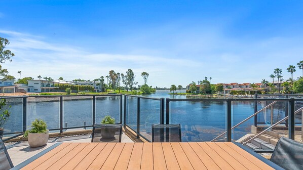 Una terraza con vista a un río, rodeada de edificios y palmeras.