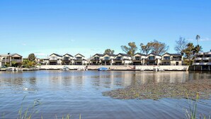 Un hotel frente al lago con varias construcciones, barcos amarrados y un lago tranquilo.