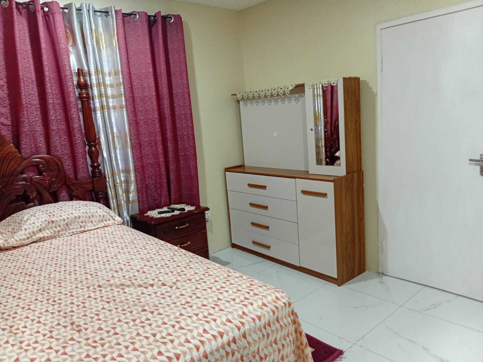 A bedroom with a bed, a dresser, a mirror, and a door.