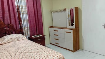 A bedroom with a bed, a dresser, a mirror, and a door.