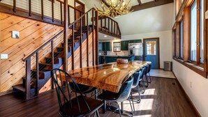 A spacious kitchen with a large island, wooden staircase, and a chandelier. - Spacious Chalet Near Stratton and Mt. Snow w/Indoor Hot Tub, Fireplace, Firepit (Wardsboro)