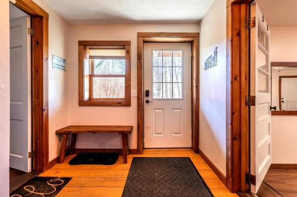 A hallway with a bench, a door, a window, and a wall-mounted sign.