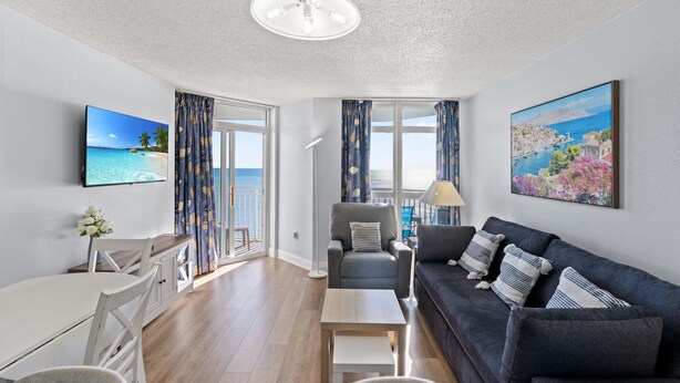 Een moderne woonkamer met een bank, fauteuil, eettafel en televisie.