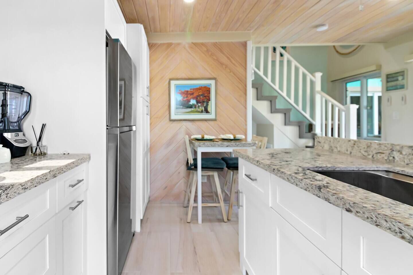 A modern kitchen with white cabinets, a granite countertop, and a stainless steel refrigerator.