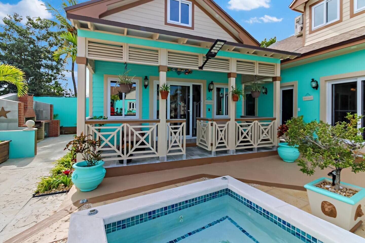 Une maison à deux étages dotée d’un patio couvert, d’une piscine et de plantes en pot.