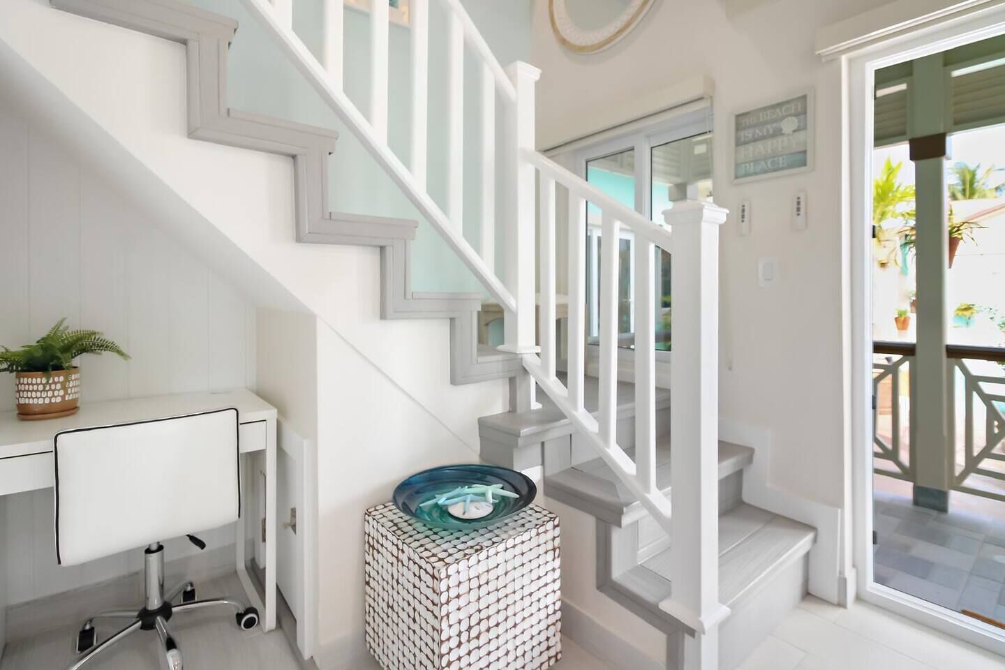 Una escalera con barandas blancas y un portón de cristal que da a un balcón.
