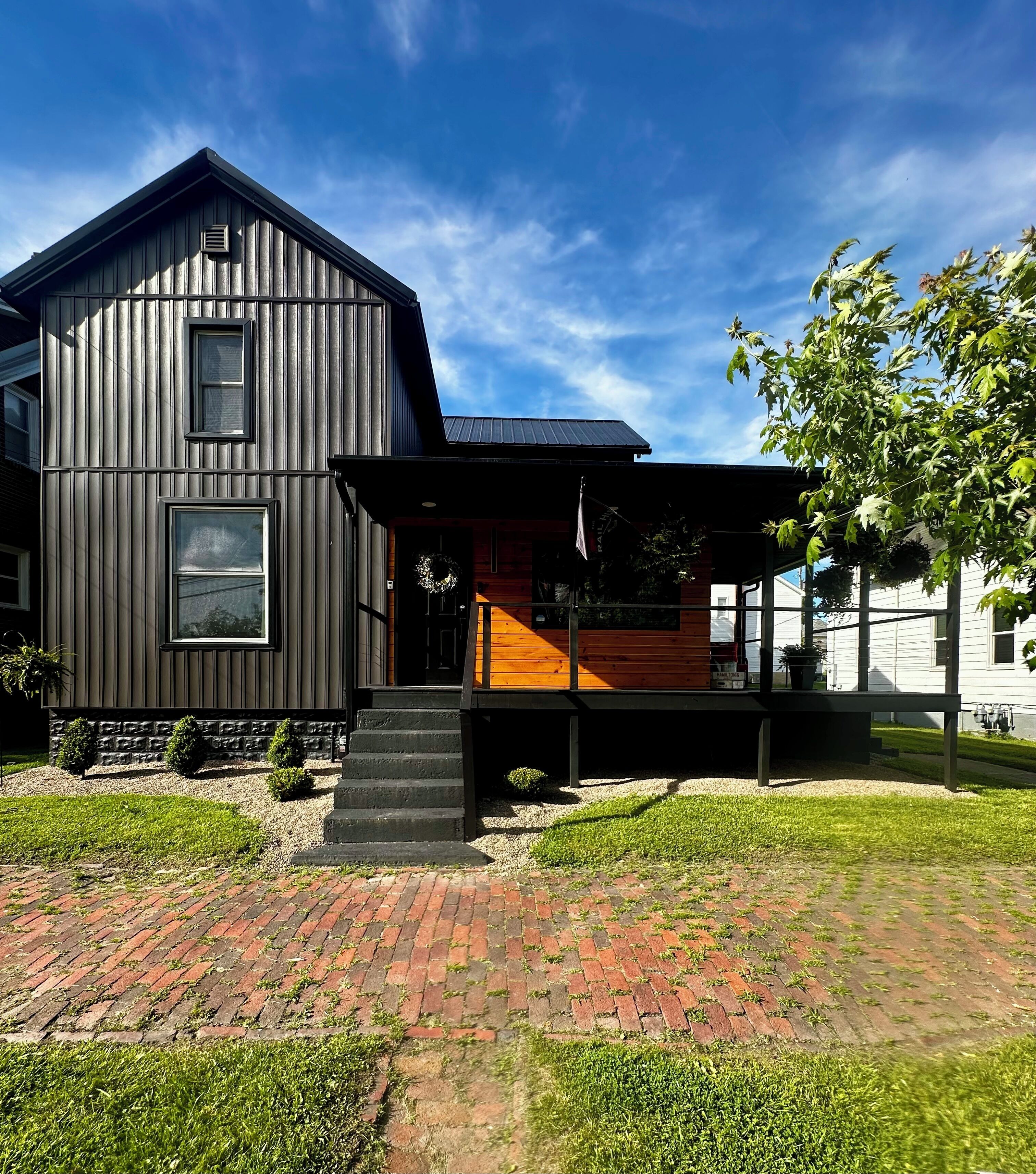 A modern two-story house with a wooden deck and a brick pathway.