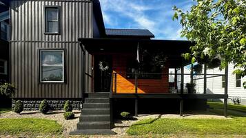 A modern two-story house with a wooden deck and a brick pathway.