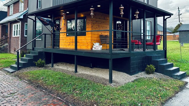 Una casa moderna de dos pisos con porche cubierto, fachada de ladrillo e interior de madera.
