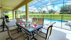 Eine Terrasse im Freien mit Glasveranda, Pool und Esstisch für vier Personen.