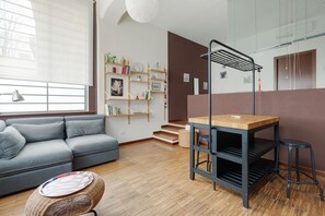 A modern living room with a grey sofa, a wooden table, and a bookshelf.