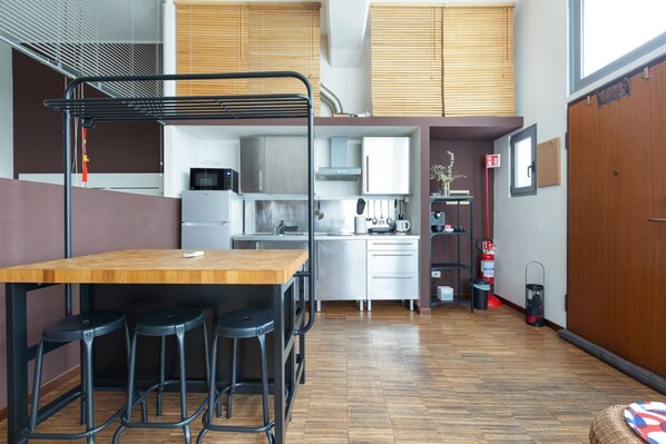 Une cuisine compacte avec une table en bois et des tabourets de bar, un four à micro-ondes et un évier.
