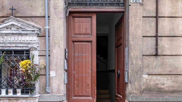 A building entrance with a large wooden door, a window with a metal grill, and a small balcony. - GuestHost - Cozy 86 sqm apartment, able to accommodate up to 6 people, located on the mezzanine floor of a characteristic building (steps to access). The property is located in a strategic position, a few steps from the famous Catacombs of the Capuchins  (Palermo)