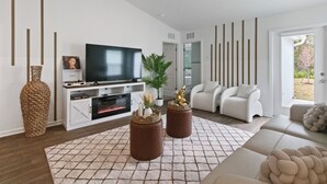 Un salon moderne avec un téléviseur à écran plat, des canapés blancs et un tapis à motifs.