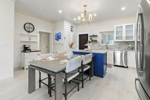 A modern kitchen with a dining area, featuring a large island, stainless steel appliances, and a chandelier. - Pineapple Premier Villa (3 Bedroom), Waterfront Bliss with boat access, Kayaks, Sandbar in the Baham (Nassau)