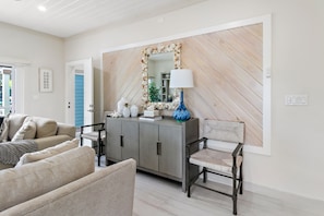 A living room with a sofa, a chair, a cabinet, and a mirror. - Pineapple Premier Villa (3 Bedroom), Waterfront Bliss with boat access, Kayaks, Sandbar in the Baham (Nassau)