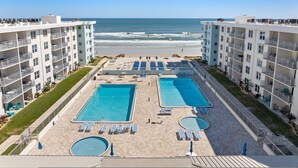 Un resort con dos piscinas, vistas a la playa y varios balcones.