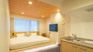 Una habitación de hotel con cama, televisión, lavamanos y un mueble de madera.