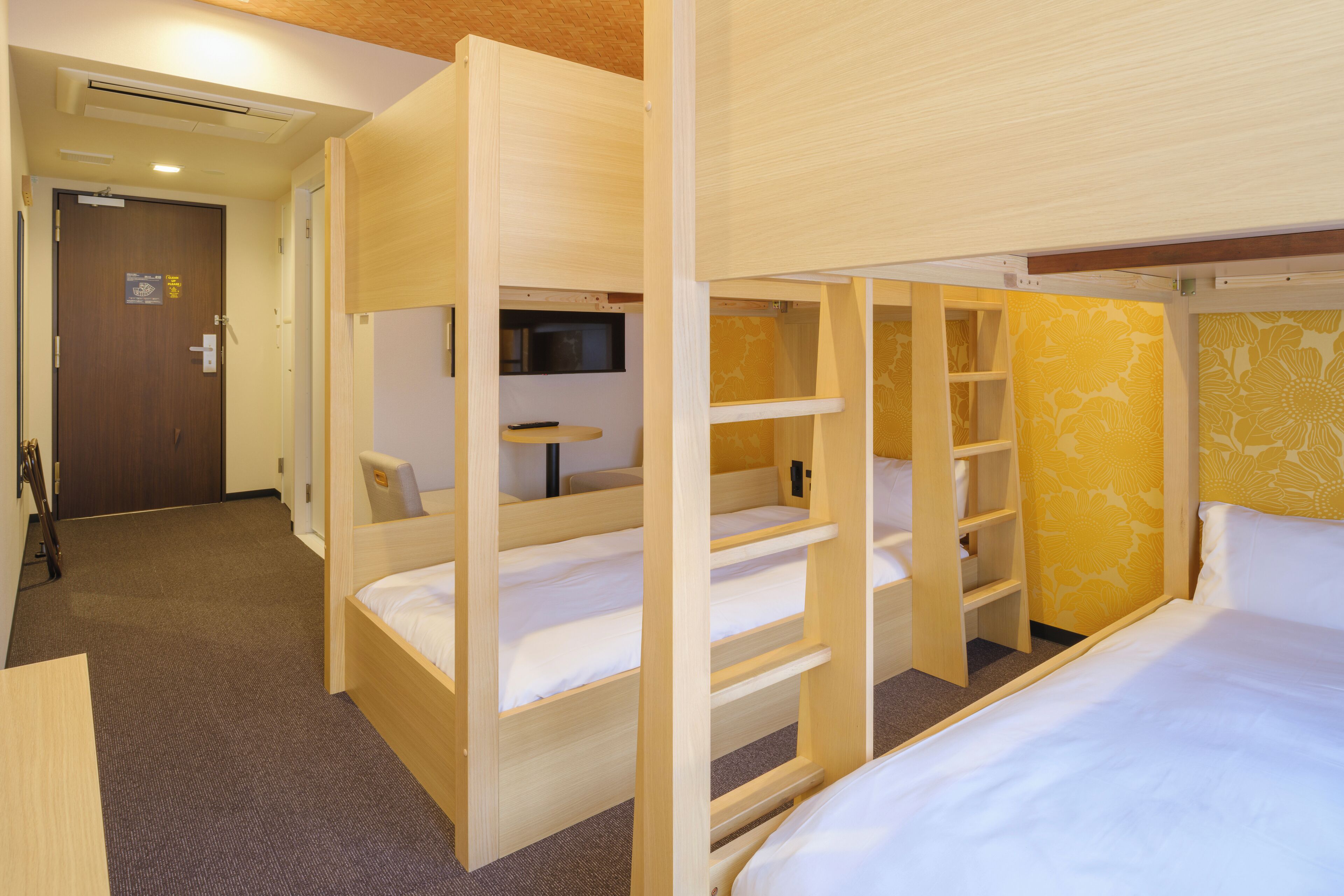 A hotel room with bunk beds, a television, and a small table.