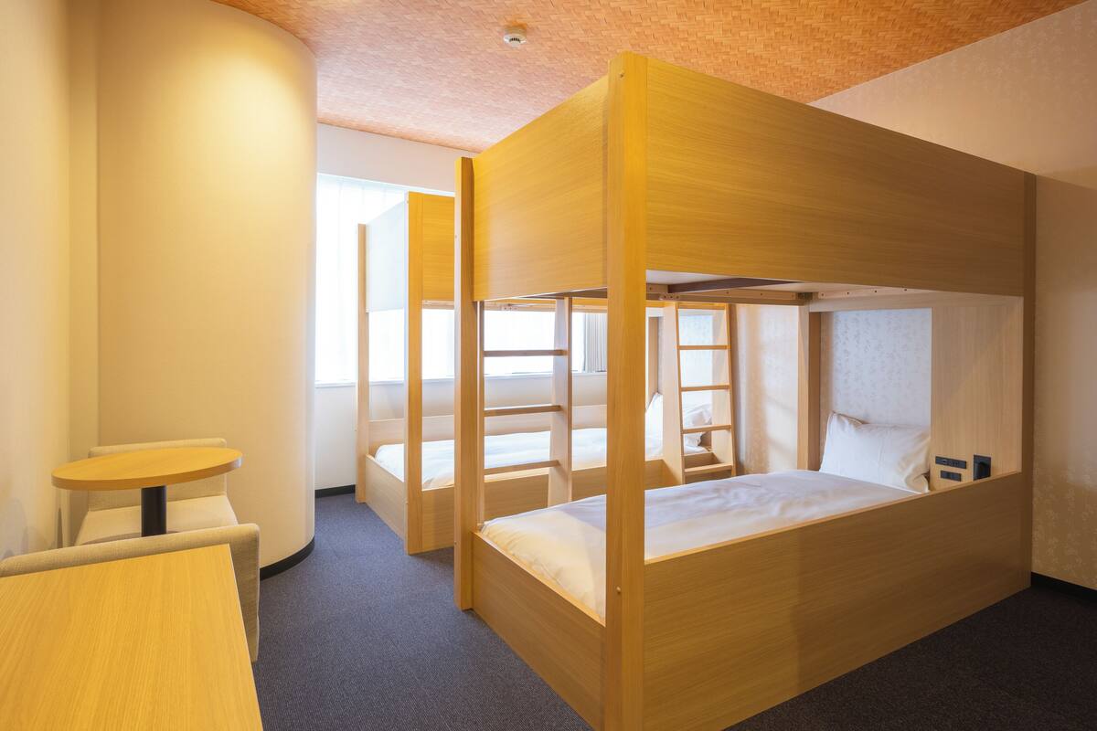 A room with bunk beds, a round table, and a window.
