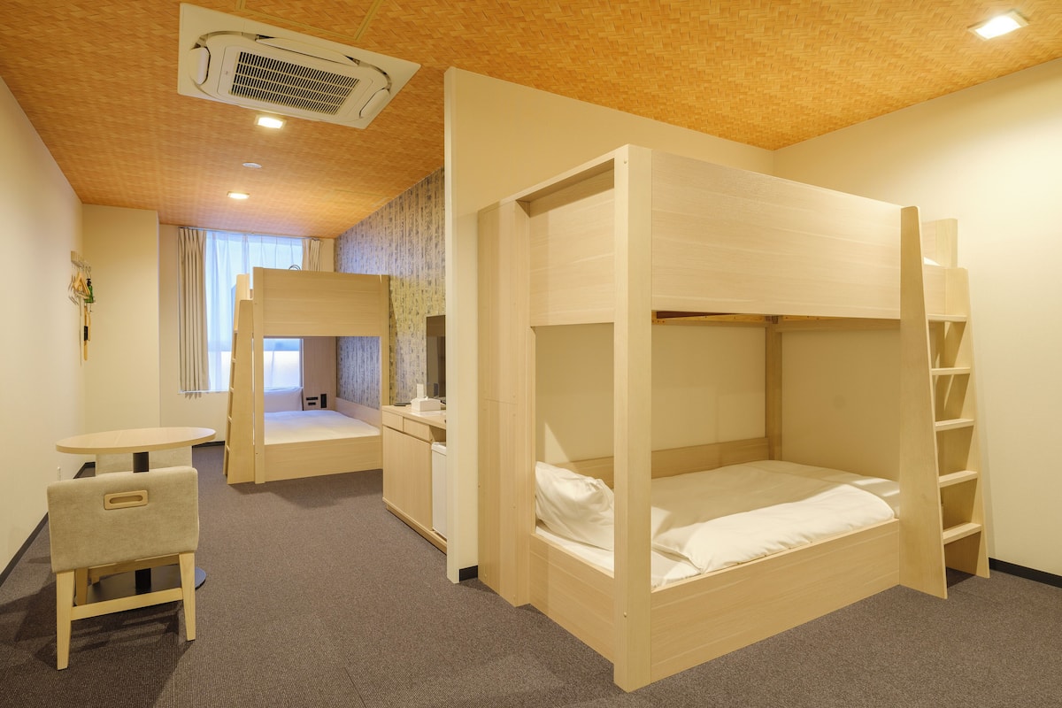 A room with bunk beds, a desk, and a chair.