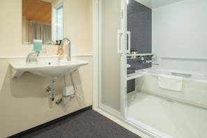 Un baño moderno con lavamanos, espejo y zona de ducha.
