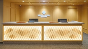 Mostrador de recepción en el Hotel Sei Cocoon con diseño moderno, dos monitores de computadora y un logotipo sobre el mostrador.