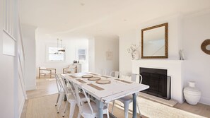 Un coin repas avec une table blanche, des chaises et une cheminée.