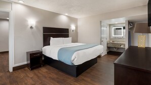 Une chambre d’hôtel moderne, dotée d’un grand lit, de tables de chevet, d’un bureau et d’une salle de bain visible à travers une porte ouverte.